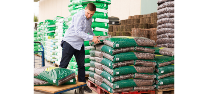 man picking up fertilizer from pallet at home hardware store