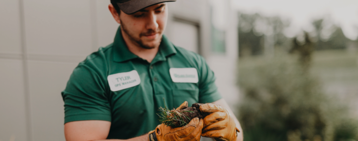 a Yard Dawgs technician holds a clump of soil and looks at it in his hands