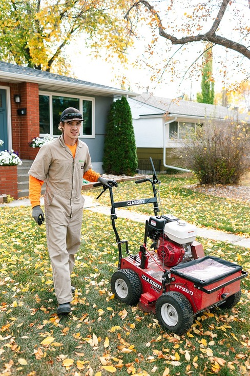 Lawn care technician using aeration equipment to repair compacted soil and restore healthy turf growth